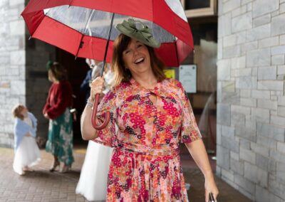 happy woman in red holding an umbrella by Anglesey wedding photographer Gill Jones