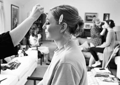 profile of a bridesmaid as her makeup is applied with two bridesmaids either side of her in the background by Anglesey wedding photographer Gill Jones