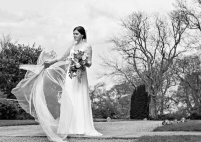 bride preventing her veil from blowing away in the wind by Anglesey wedding photographer Gill Jones