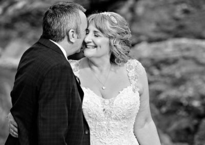 bride and groom snuggle by Anglesey wedding photographer Gill Jones