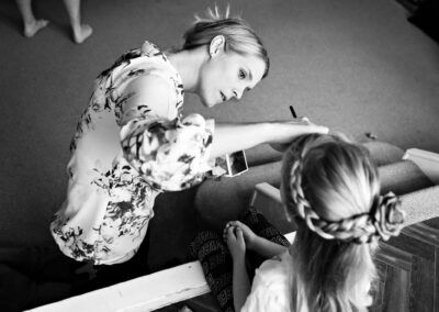 make up artist leans to apply make up to a bridesmaid by Anglesey wedding photographer Gill Jones