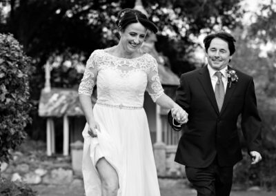 bride leads the groom by hand as they run together by Anglesey wedding photographer Gill Jones