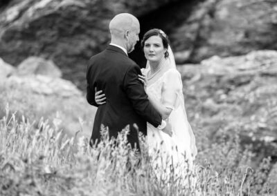 bride and groom caressing, the bride looks away from her groom for a moment by Anglesey wedding photographer Gill Jones