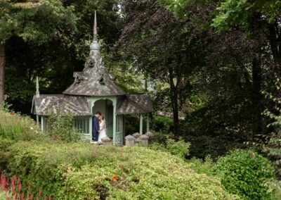 bride and groom cuddling in a summer house in the grounds of Chateau Rhianfa by Anglesey wedding photographer Gill Jones
