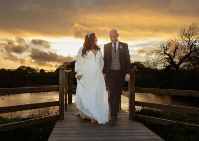 bride and groom walking along a jetty at sunset by Anglesey wedding photographer Gill Jones