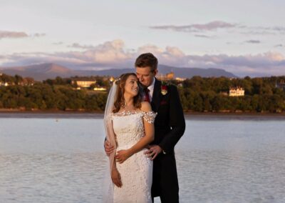 bride and groom embracing with their backs towards a mountain range by Anglesey wedding photographer Gill Jones