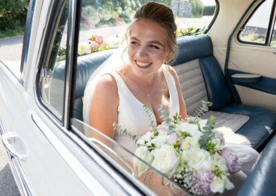 bride looking out of the window of her wedding car, smiling by Anglesey wedding photographer Gill Jones photography