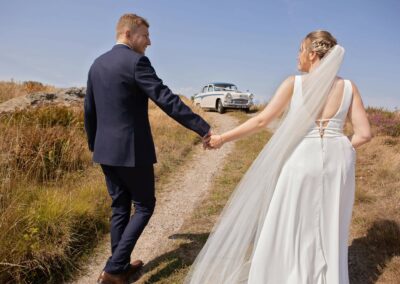 bride and groom walking hand in hand towards their wedding card by Anglesey wedding photographer Gill Jones photography