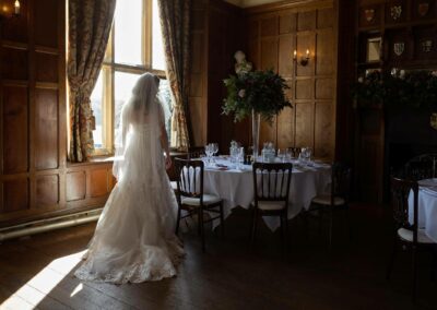 bride standing by a dining table looking at the place settings by Anglesey wedding photographer Gill Jones Photography