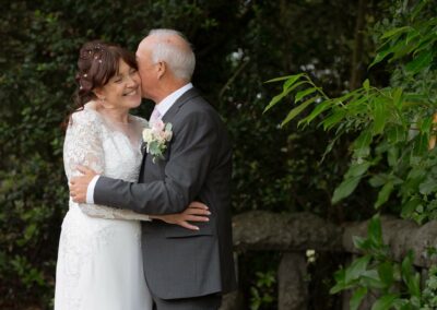 groom kissing his bride on the cheek by Anglesey wedding photographer Gill Jones Photography