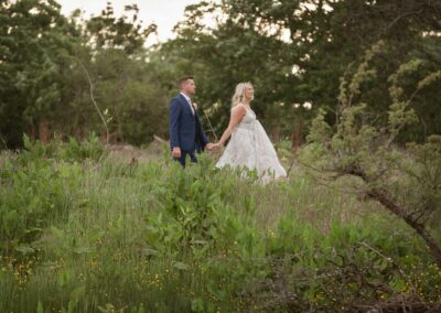 bride leading groom through the green grass by Anglesey photographer Gill Jones Photography