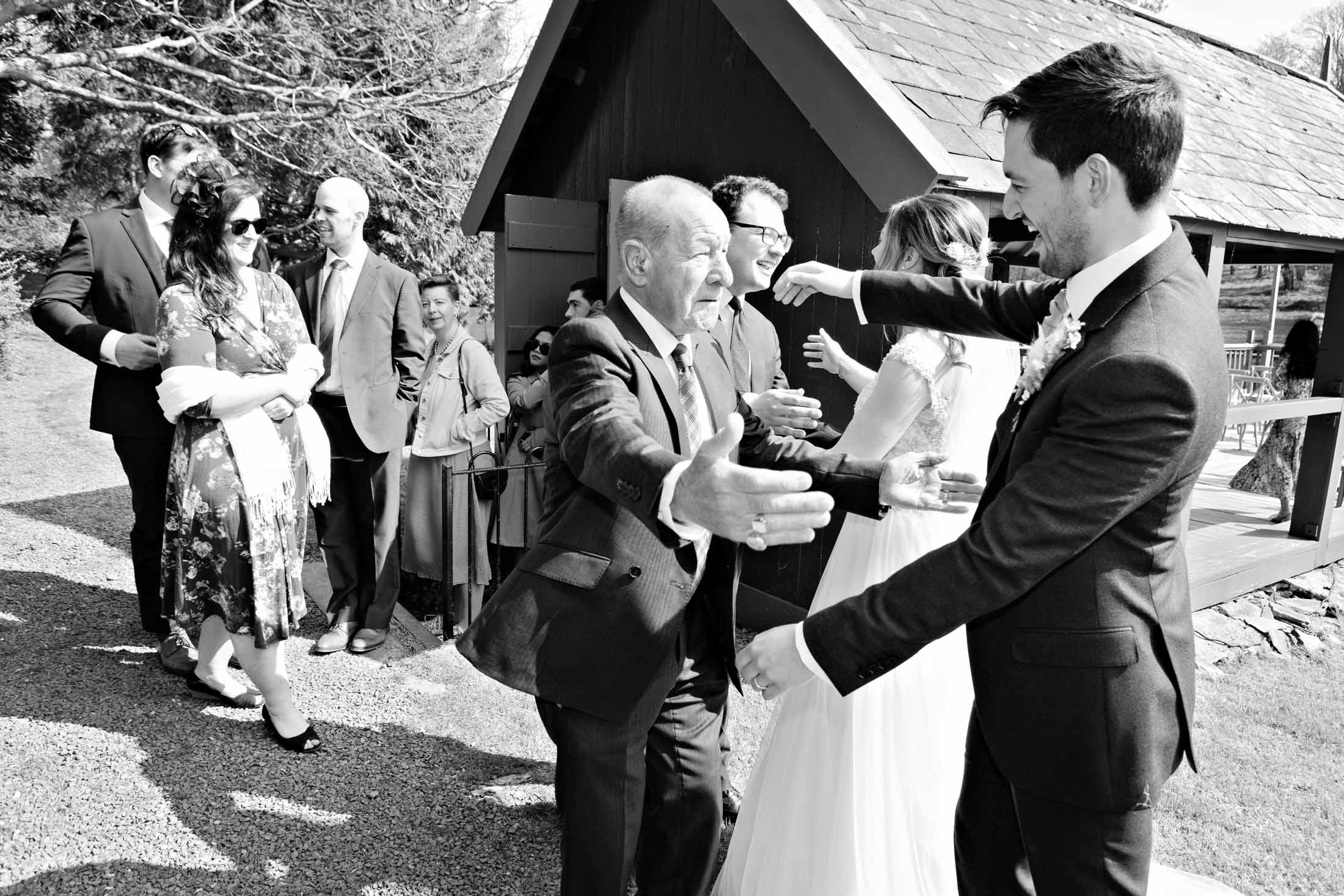 bride smiles a huge smile as her friend buttons her wedding dress from behind by Anglesey wedding photographer Gill Jones Photography