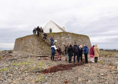 Wedding Guests make their way up the stone staircase towards St.Cwyfan's Church by Anglesey Photographer Gill Jones Photography