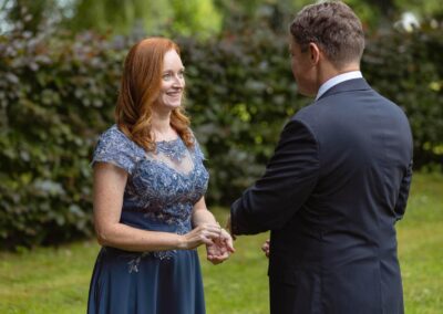 a woman wearing a blue dress gestures with surprise at her husband by Anglesey elopement photographer Gill Jones Photography