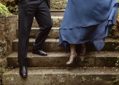 a couple walk down stone steps slowly by Anglesey elopement photographer Gill Jones Photography