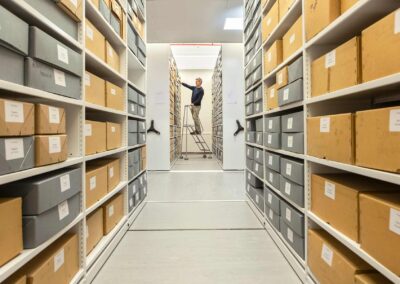 a man standing on a ladder reaches for a box in an archive gallery by north wales commercial photographer Gill Jones Photography