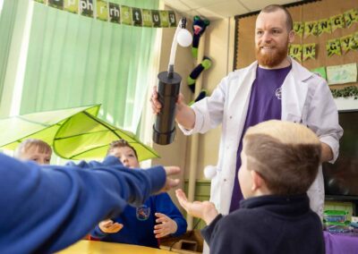 a scientist offers a bubble blowing machine to school boys by north wales commercial photographer Gill Jones Photography